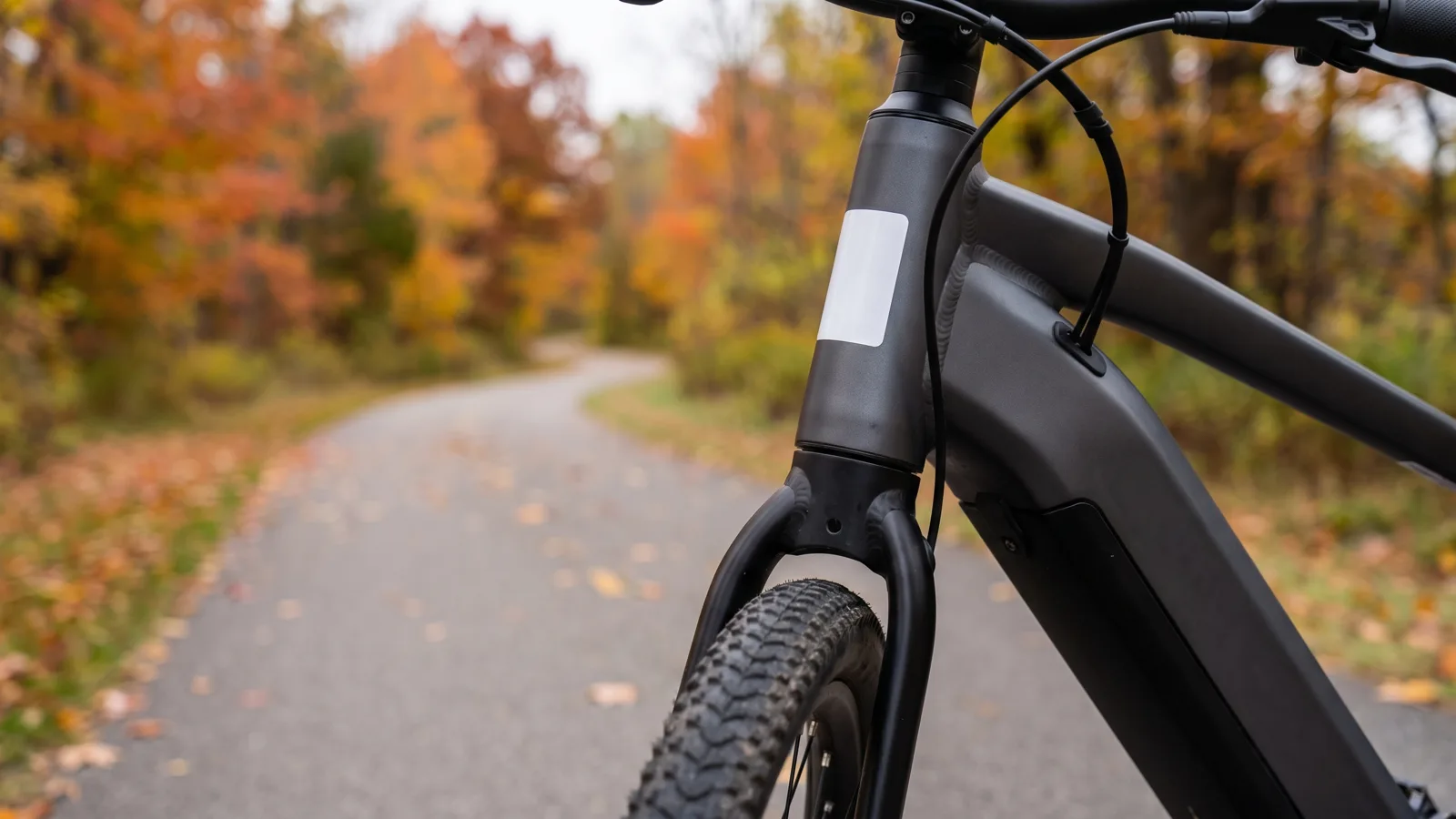 E-bike head tube with a blank registration sticker on a paved Ohio trail in autumn.