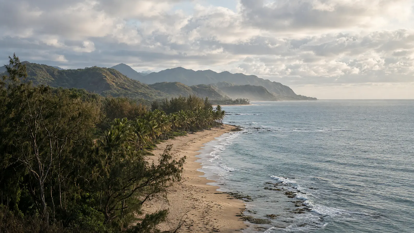 East Kauai coast near Kapaʻa: pale sand, ironwood shoreline, and low coastal mountains