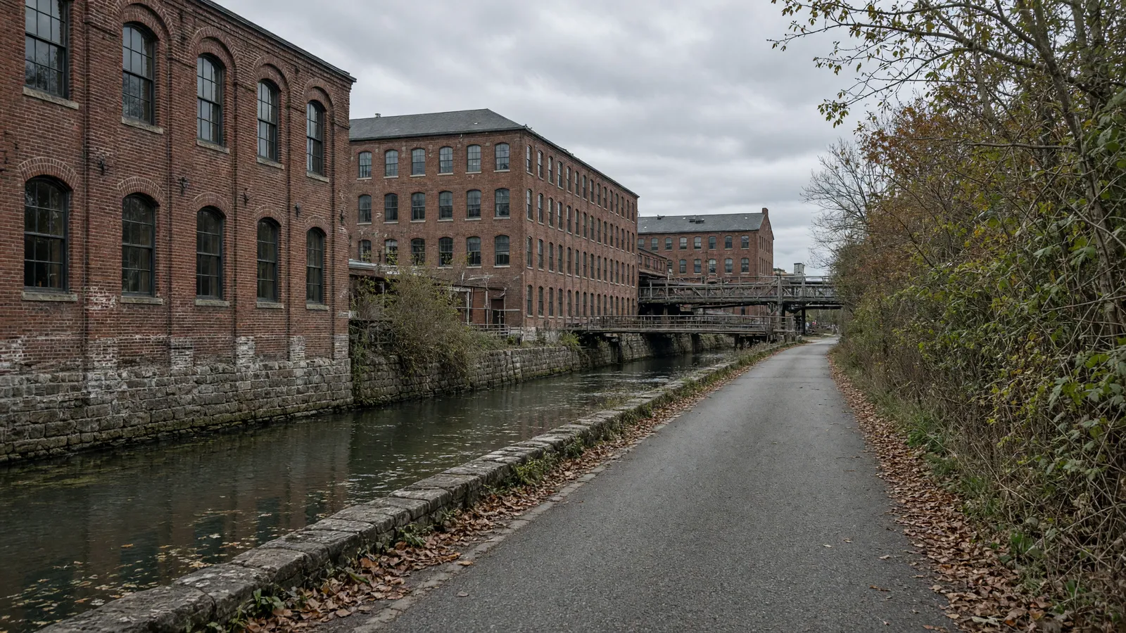 Empty Blackstone River Bikeway paved path along mill-race canal and brick mills near Worcester, Worcester County, Massachusetts