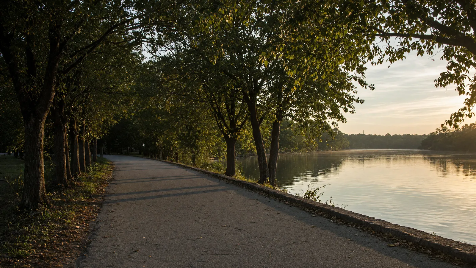 Empty Cooper River paved path through trees along still water, Camden County, New Jersey