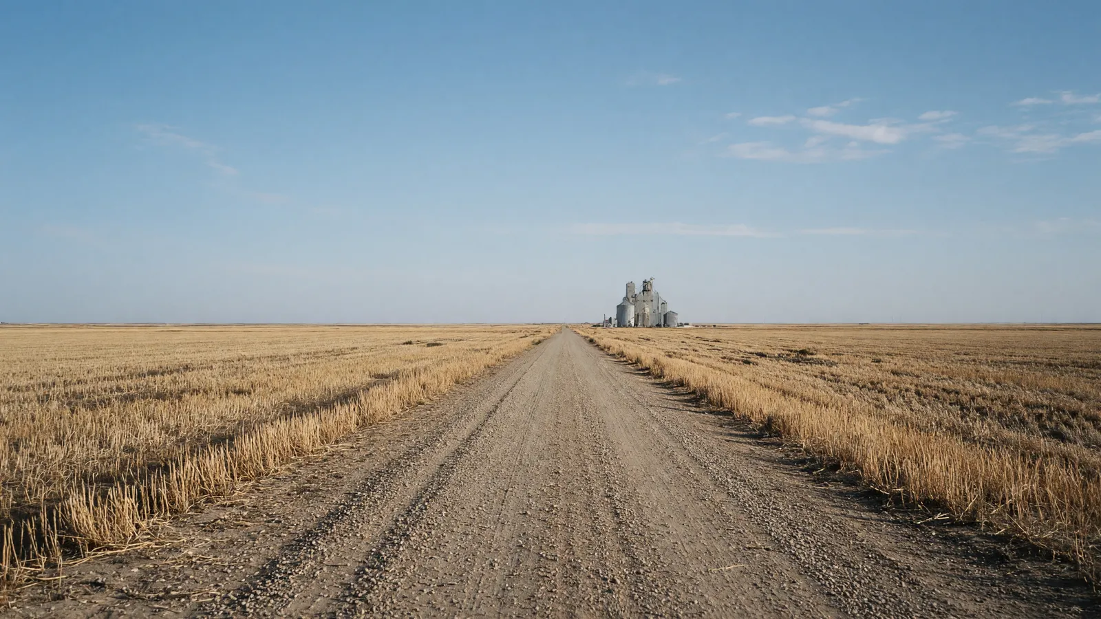 Empty Clovis high-plains farm road through wheat stubble toward a wide sky, Curry County, New Mexico
