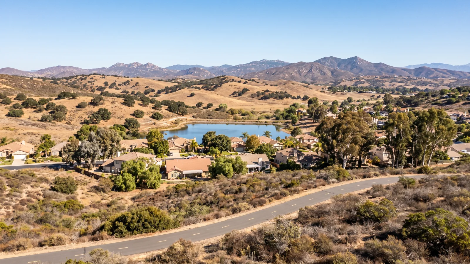 Paved bike path beside an inland lake and rolling hills in San Marcos California