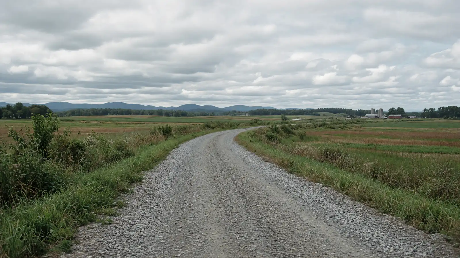 Empty crushed-stone rail-trail through farm flats in Franklin County, Vermont