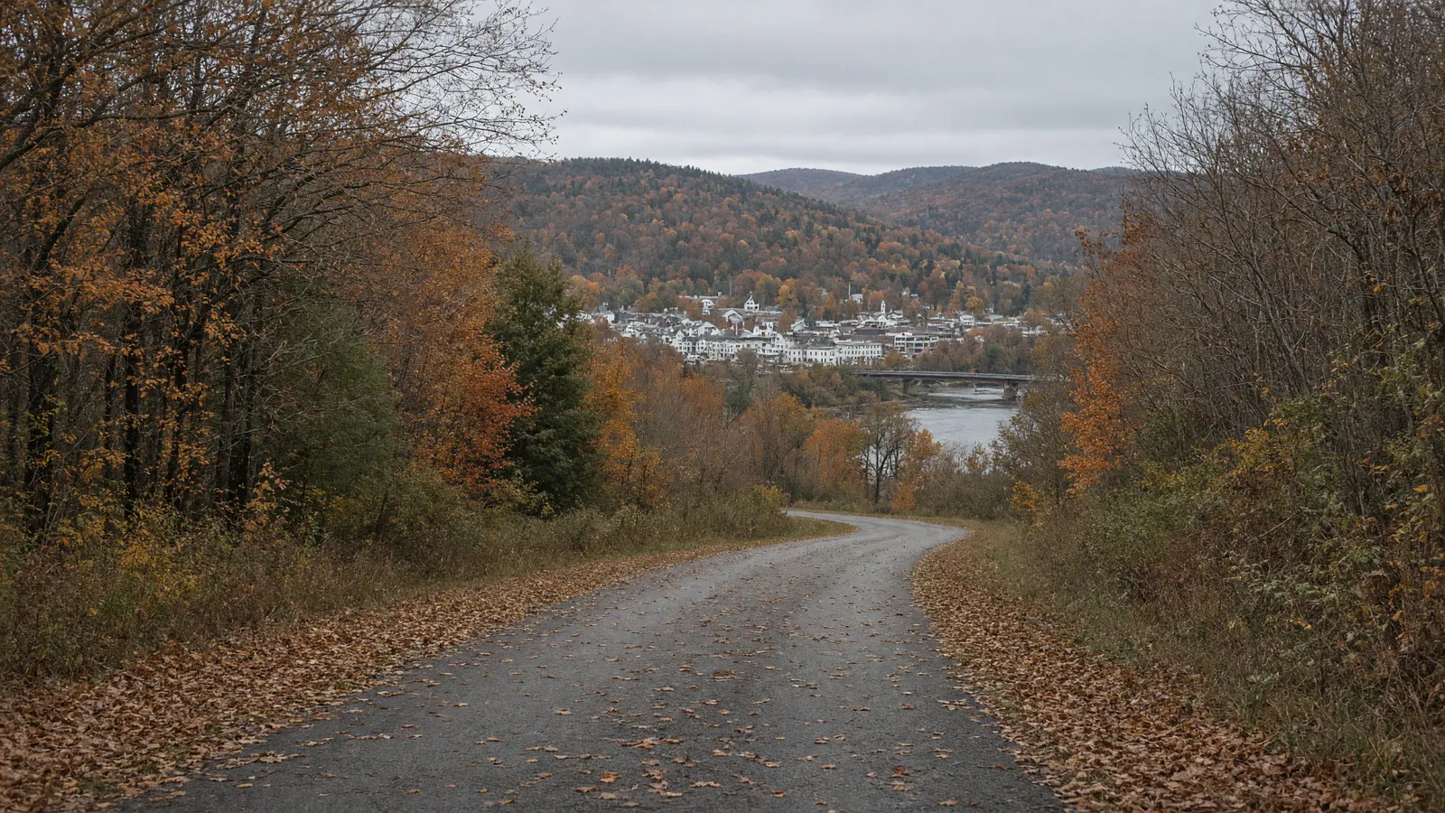 Empty paved rail-trail corridor toward a river town in Windsor County, Vermont